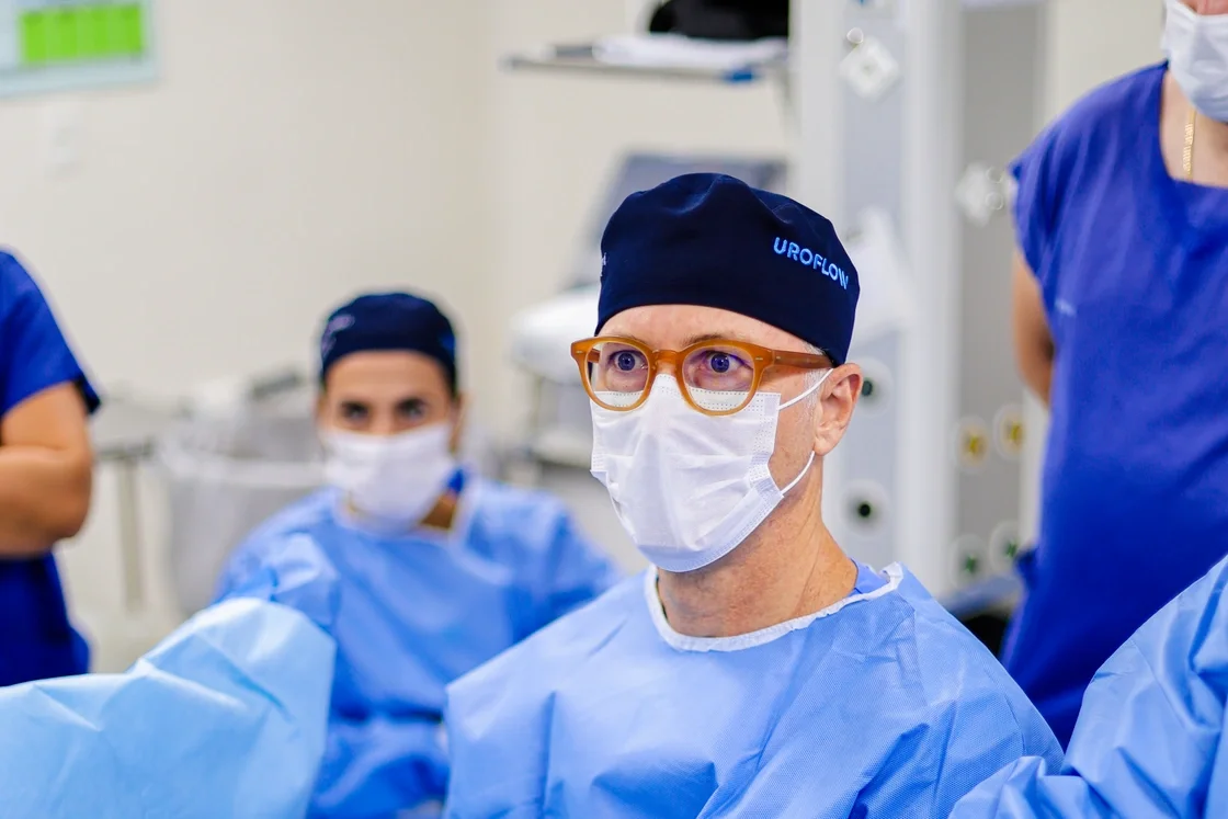 Dr. Alberto ao centro e dois membros da equipe paramentados, durante uma cirurgia.