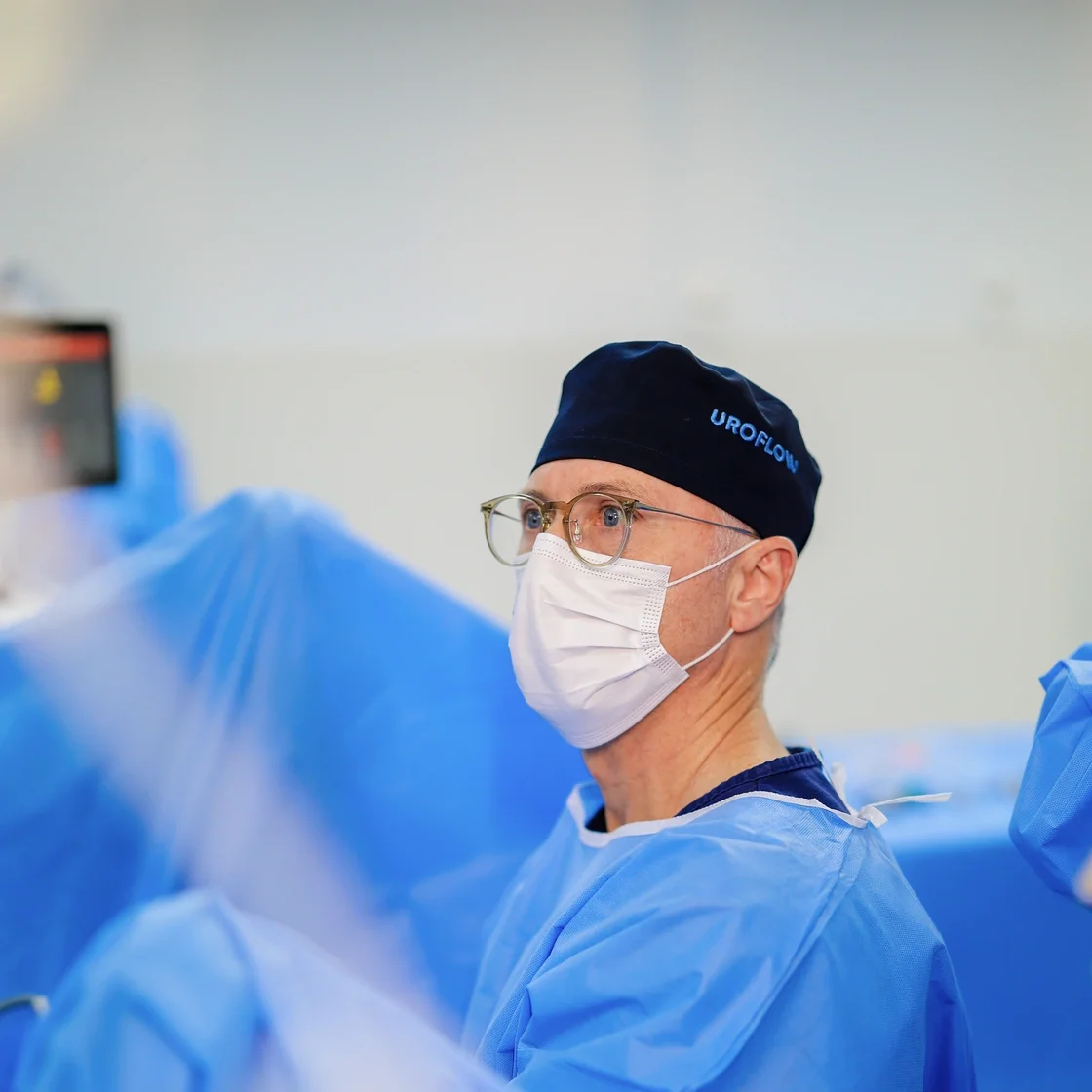 Dr. Alberto paramentado em centro cirúrgico, de touca e máscara, durante um procedimento.
